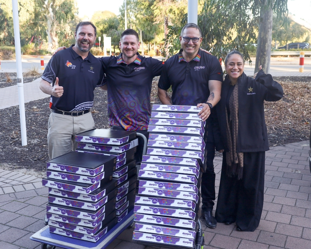 Danjoo and Shooting Stars staff with two tall stacks of laptops on trolleys