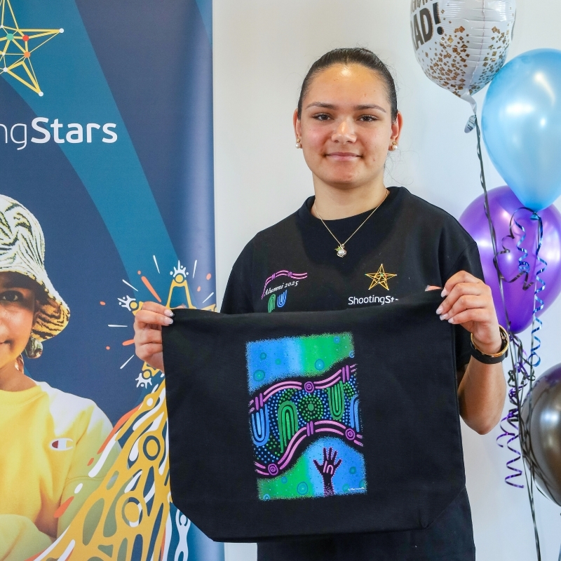 Skye holding tote bag with Alumni artwork