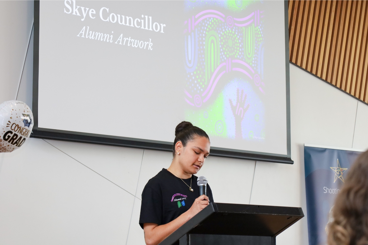 Skye speaking at lectern at Alumni Graduation