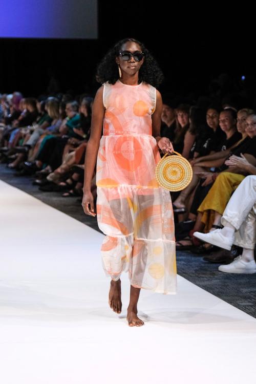 Kahlia walking on the runway in a long dress holding a bag